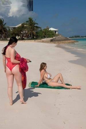 Busty lesbian girls let their huge knockers loose to kiss & lick on the beach on fansgirls.net