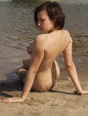 Amateur girl covers her naked body in sand while at a nude beach on fansgirls.net