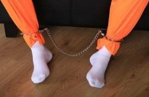 Female prisoner is left alone while cuffed in an orange jumper and white socks on fansgirls.net