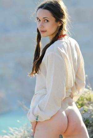 Teen model Ilona B poses nude in pigtails high above ocean waters on fansgirls.net