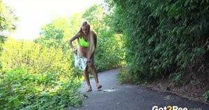 Blonde teen Daisy Lee takes a piss on a paved path through the woods on fansgirls.net