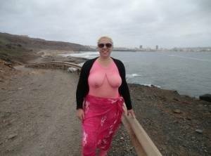 Aged lady Barby looses her big tits from a crotchless bodystocking by the sea on fansgirls.net