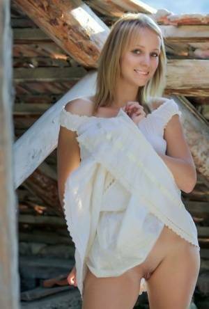 Young blonde Ilona D gets naked in a rustic setting with her boots on on fansgirls.net