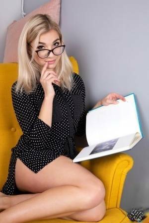 Geeky blonde Amelia undresses on a chair before playing with her shaved pussy on fansgirls.net