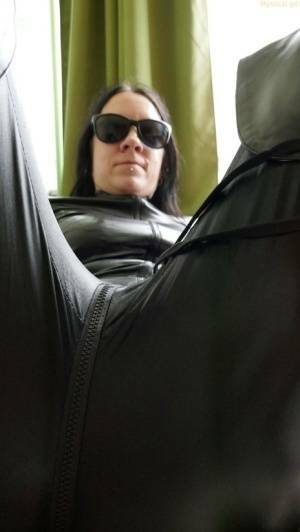 Dark haired amateur models a leather catsuit while wearing dark sunglasses on fansgirls.net
