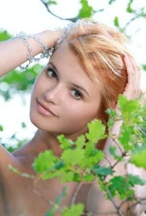 Adorable redhead Violla A displays her naked teen body atop a rock outdoors on fansgirls.net